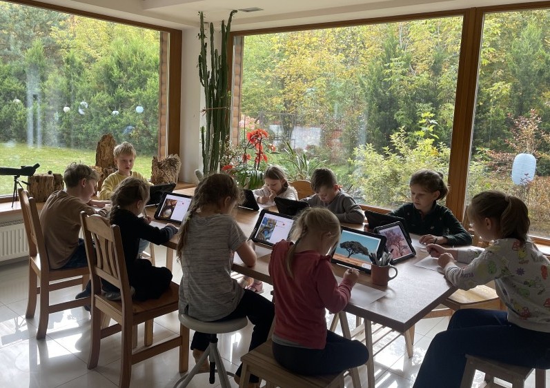 Vaikai studijoje kuria didelį koliažą ant grindų – bendradarbiavimas ir kūrybiniai eksperimentai pagal Reggio Emilia